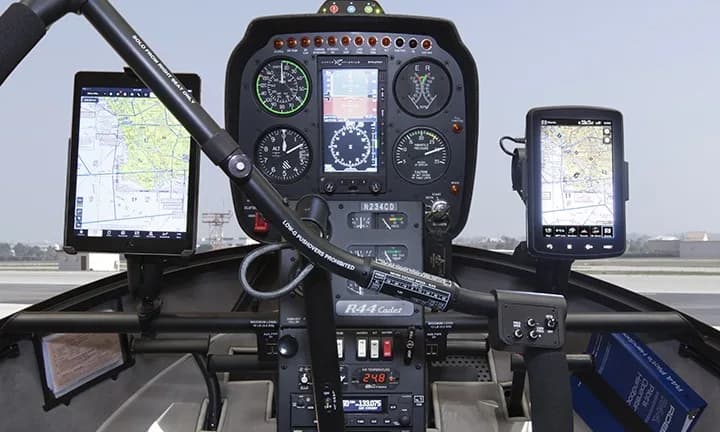 The cockpit of a Robinson R44 Cadet helicopter, showing the instrument panel and avionics.