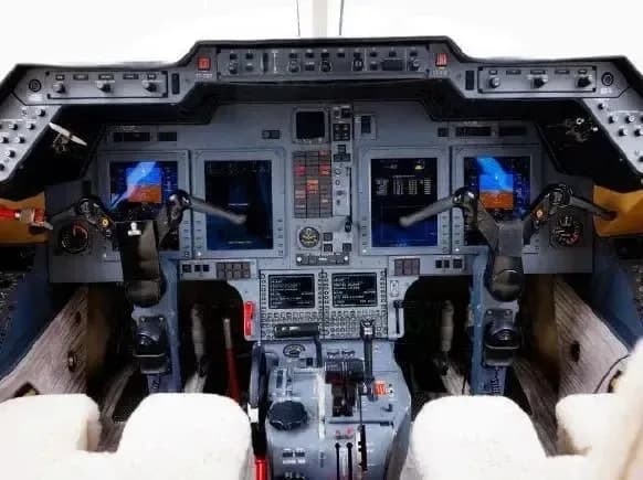 The cockpit of a jet aircraft with multiple displays and controls.