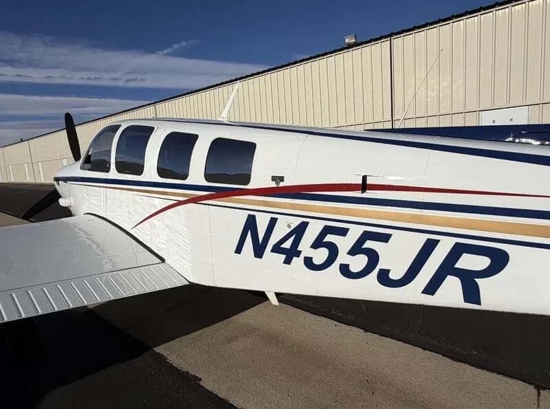 A close-up of the fuselage of the white Beechcraft Bonanza, clearly showing the N-number N455JR and paint scheme.