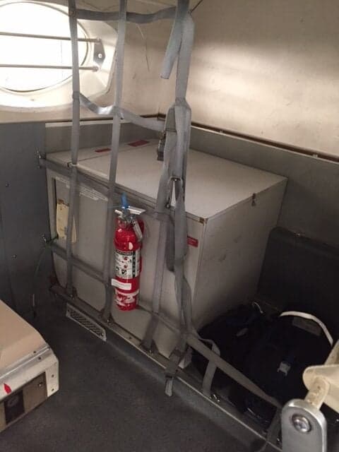 A view of the interior of the aircraft, showing a storage area with a fire extinguisher.