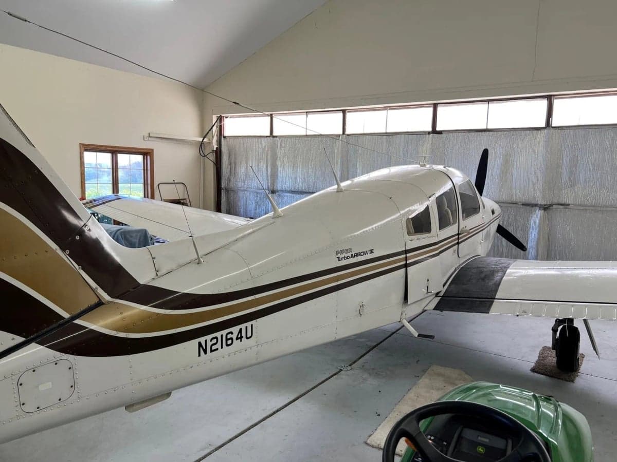 A Piper Turbo Arrow III aircraft with tail number N2164U parked inside a hangar.