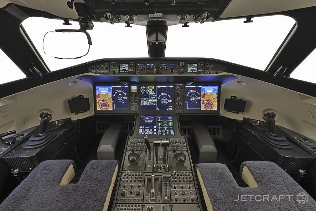 The modern cockpit of a Bombardier Global 7500 business jet with multiple digital displays and side-stick controls.