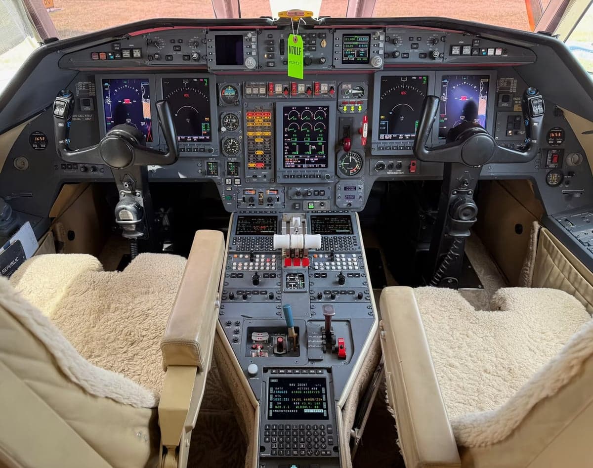 The cockpit of an aircraft features a full instrument panel and sheepskin seat covers.