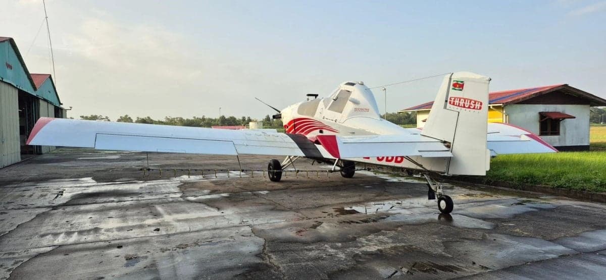 A rear-side view of a white and red Thrush 510G crop duster aircraft parked on a tarmac.