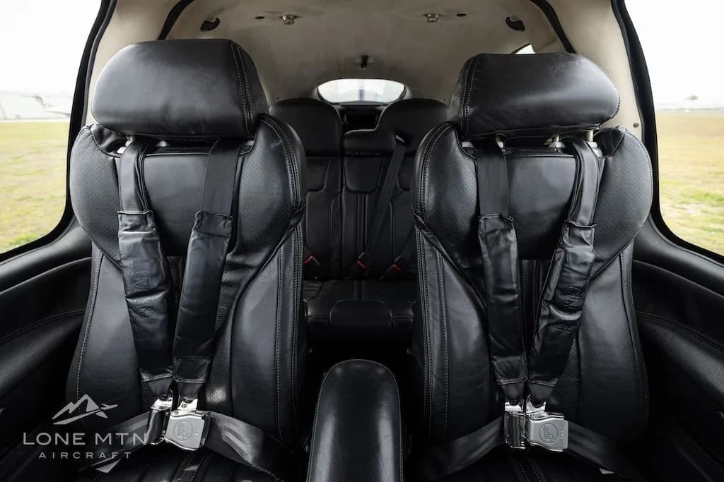 View of the black leather front and rear seats inside the aircraft cabin.
