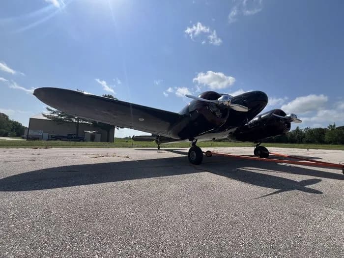 A black Lockheed 12 Electra Junior parked on a paved surface.
