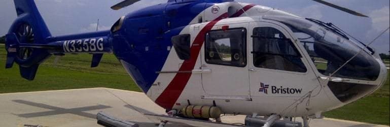 A Bristow helicopter with blue and white paint scheme is parked on the tarmac.