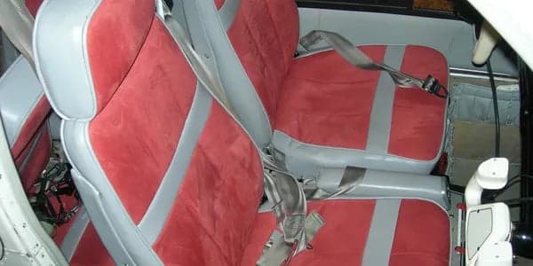 Red and gray aircraft seats with seatbelts.