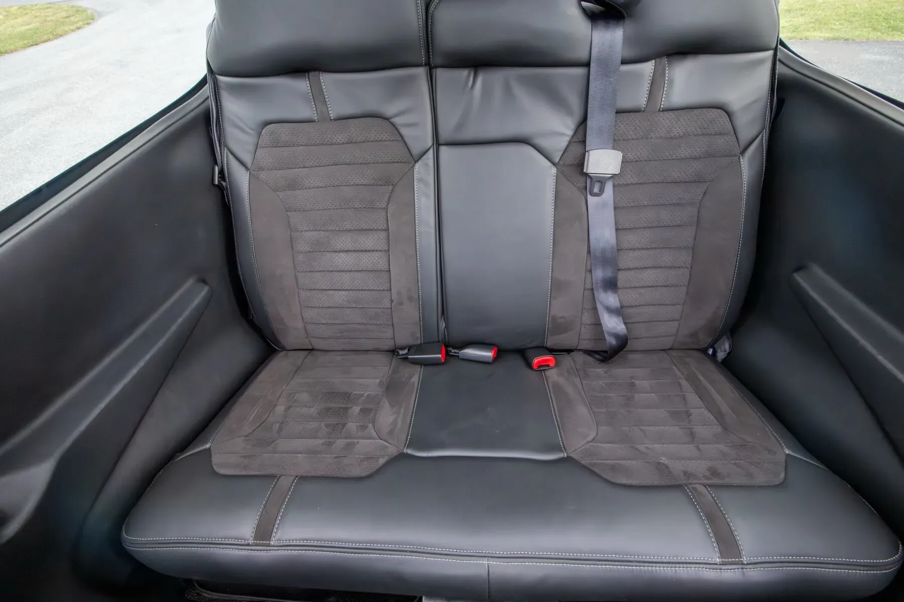 Close-up view of the black leather and suede rear seats in the aircraft cabin.