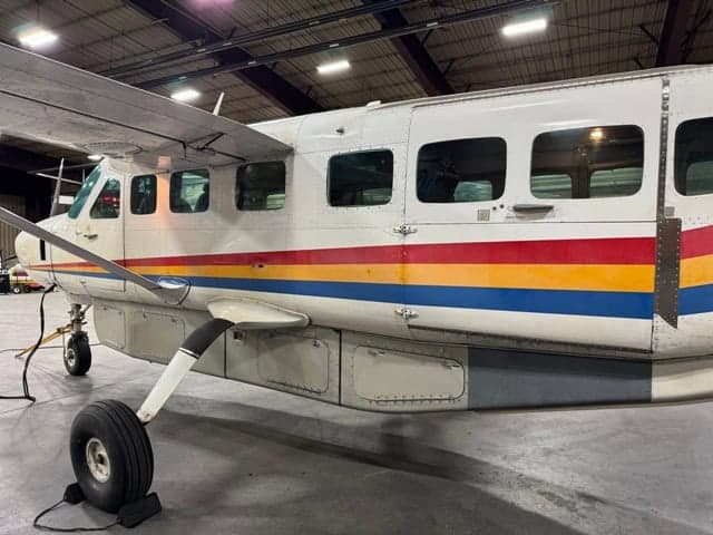 Side view of a turboprop aircraft with a colorful stripe, parked inside a hangar.