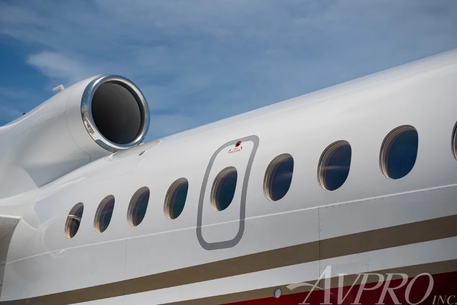 Close-up view of the fuselage, passenger windows, and an emergency exit door of the Dassault Falcon 900LX.
