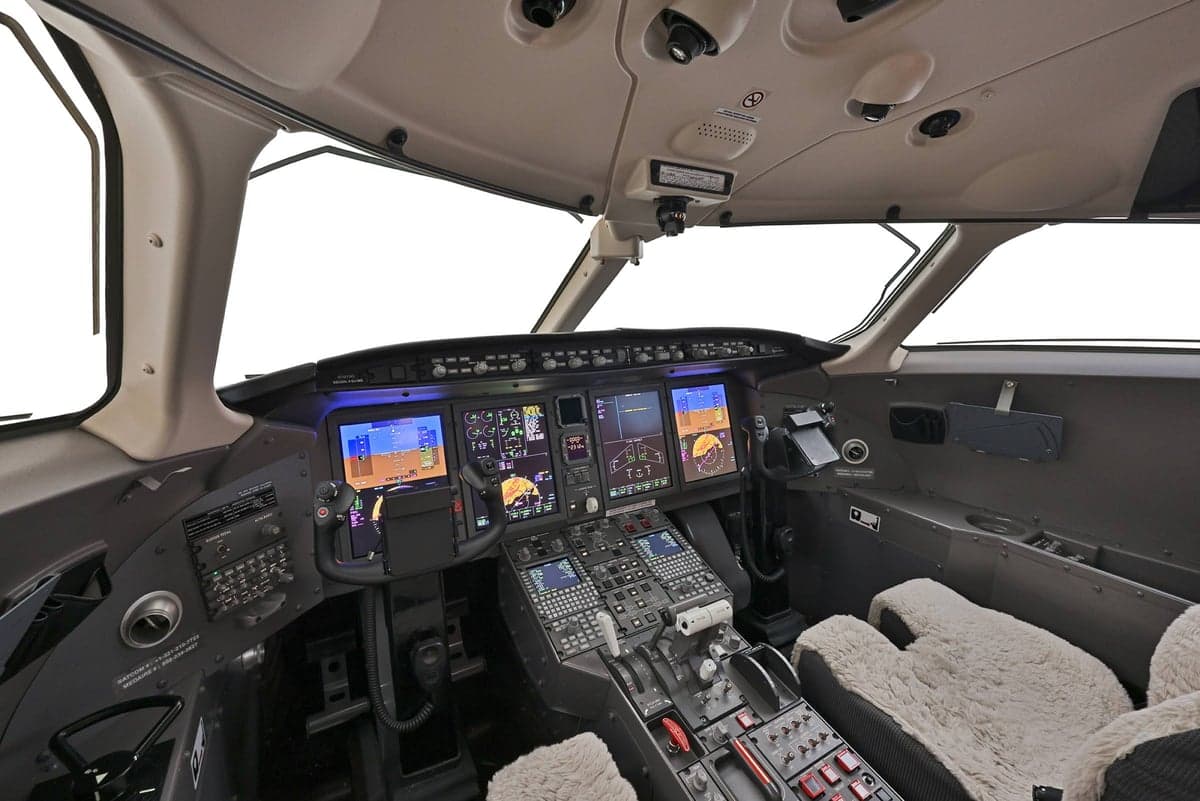 View of the aircraft's cockpit with multiple screens and controls.