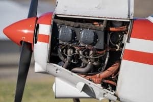 Close-up of the engine compartment of a Piper Super Cub aircraft with the cowling open.