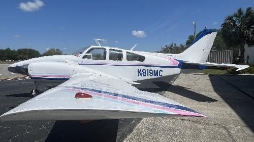 A side view of the white and blue Piper Aztec N819MC.