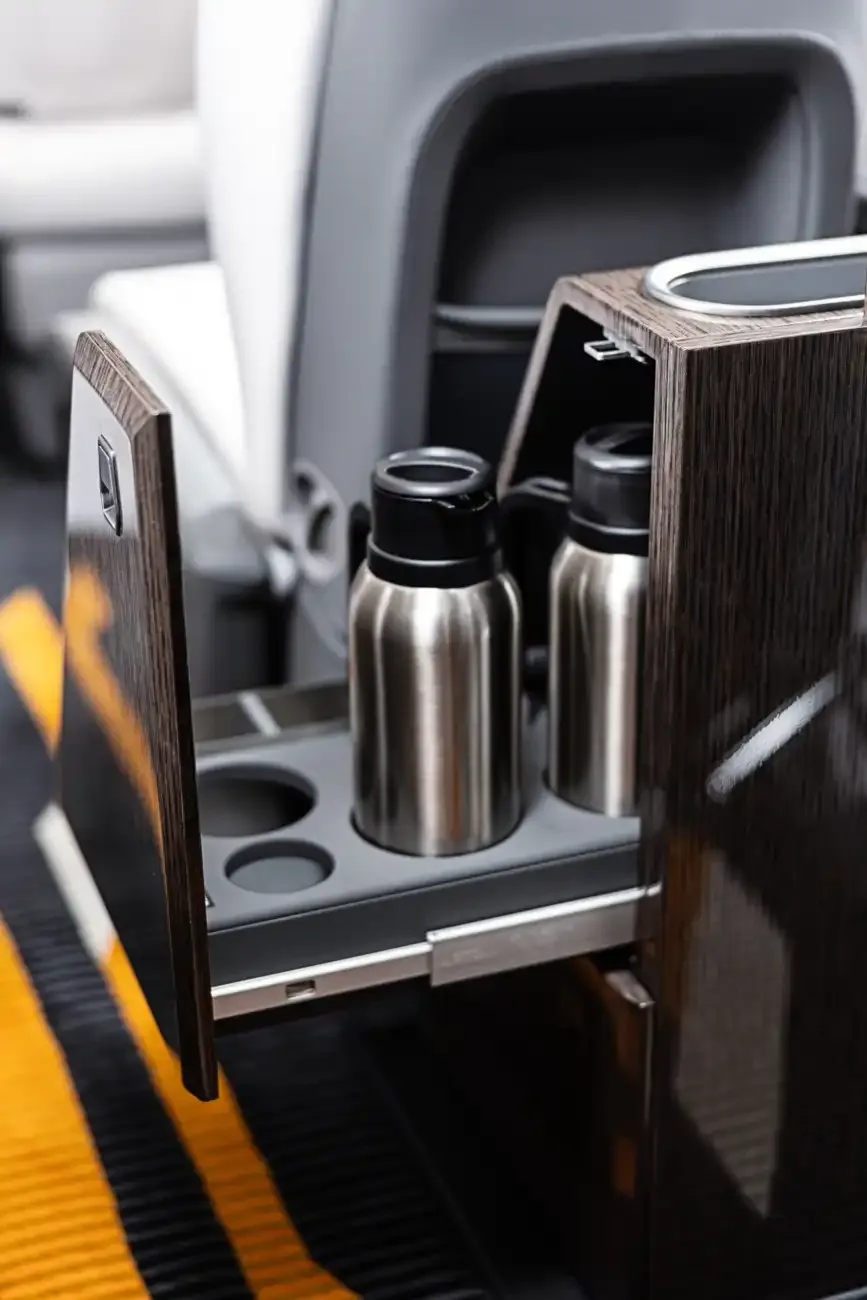Close-up of the aircraft's interior showing a wooden side console with cupholders and water bottles.
