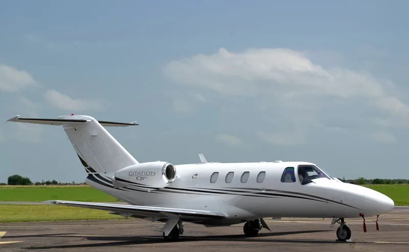A Citation CJ1+ sits on the tarmac under a partly cloudy sky.