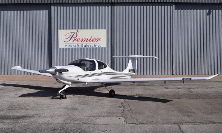 Diamond DA40 aircraft with registration N125HL parked in front of a hangar with a Premier Aircraft Sales sign.