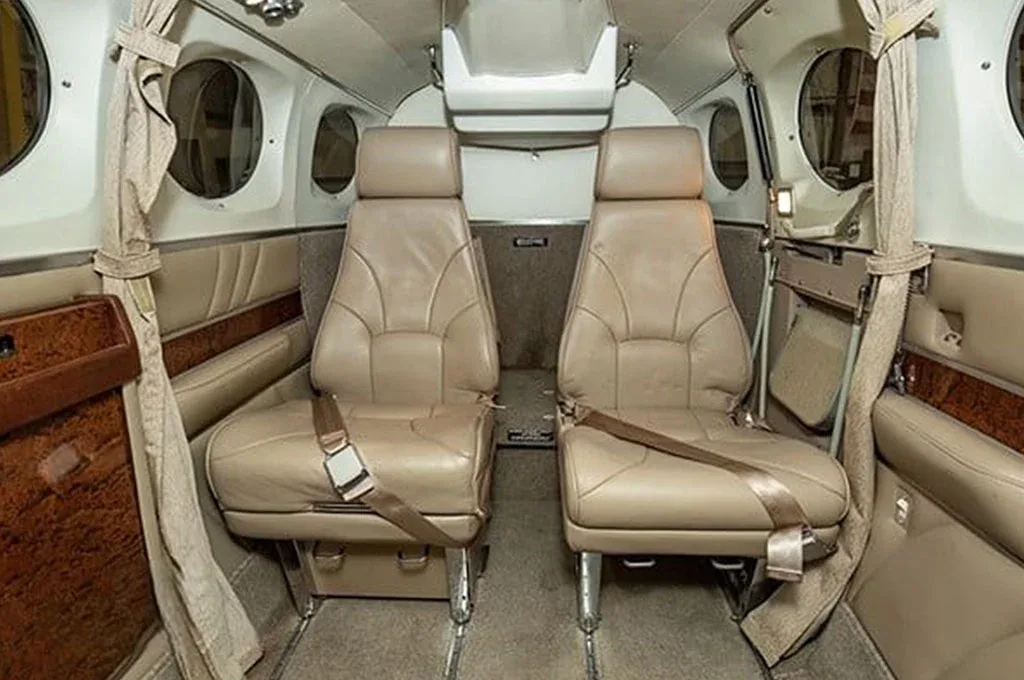 The aircraft's interior cabin with two tan leather passenger seats facing forward.