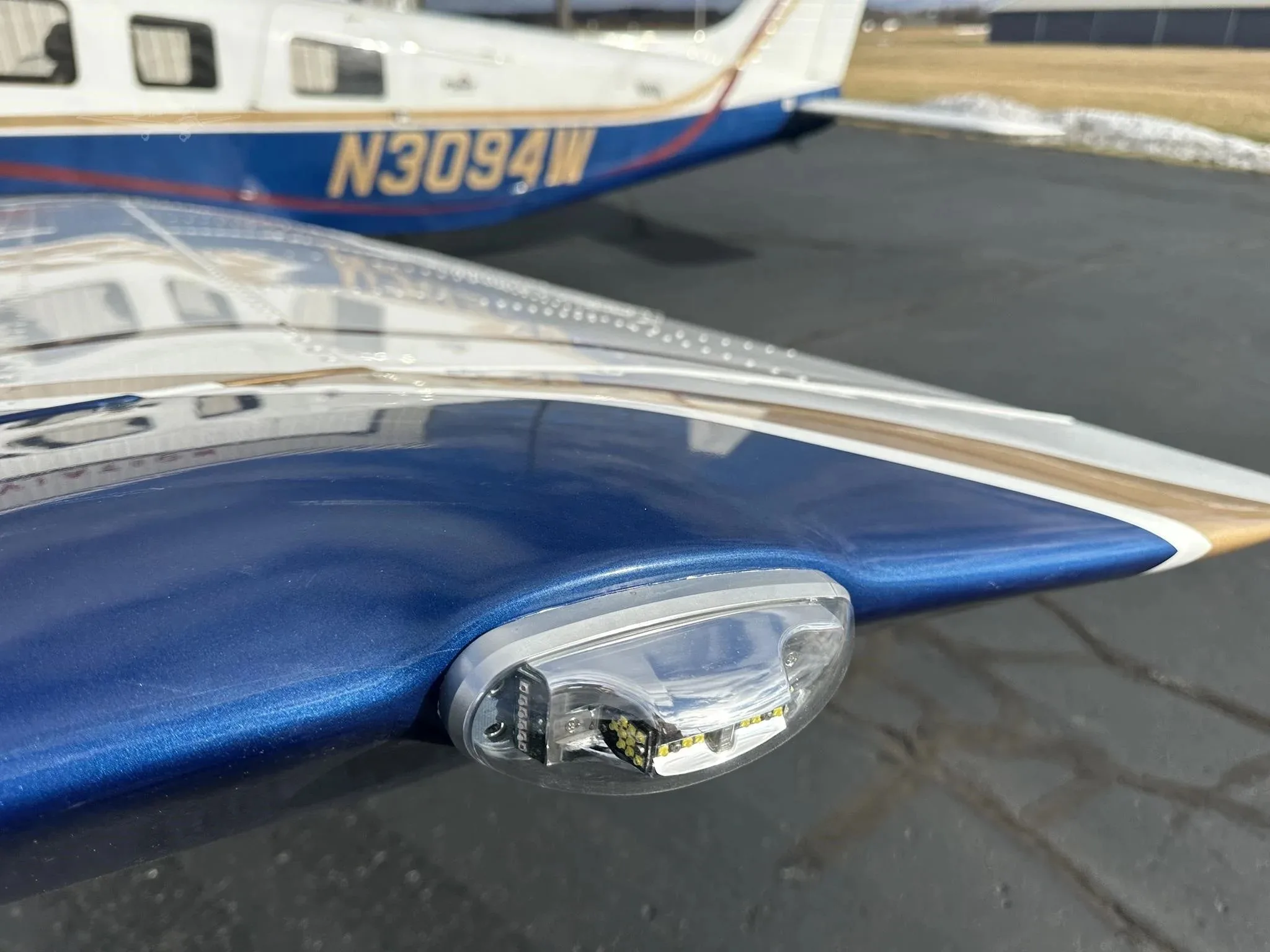 A close-up of the wingtip light on the blue and white Piper Malibu Mirage N3094W.