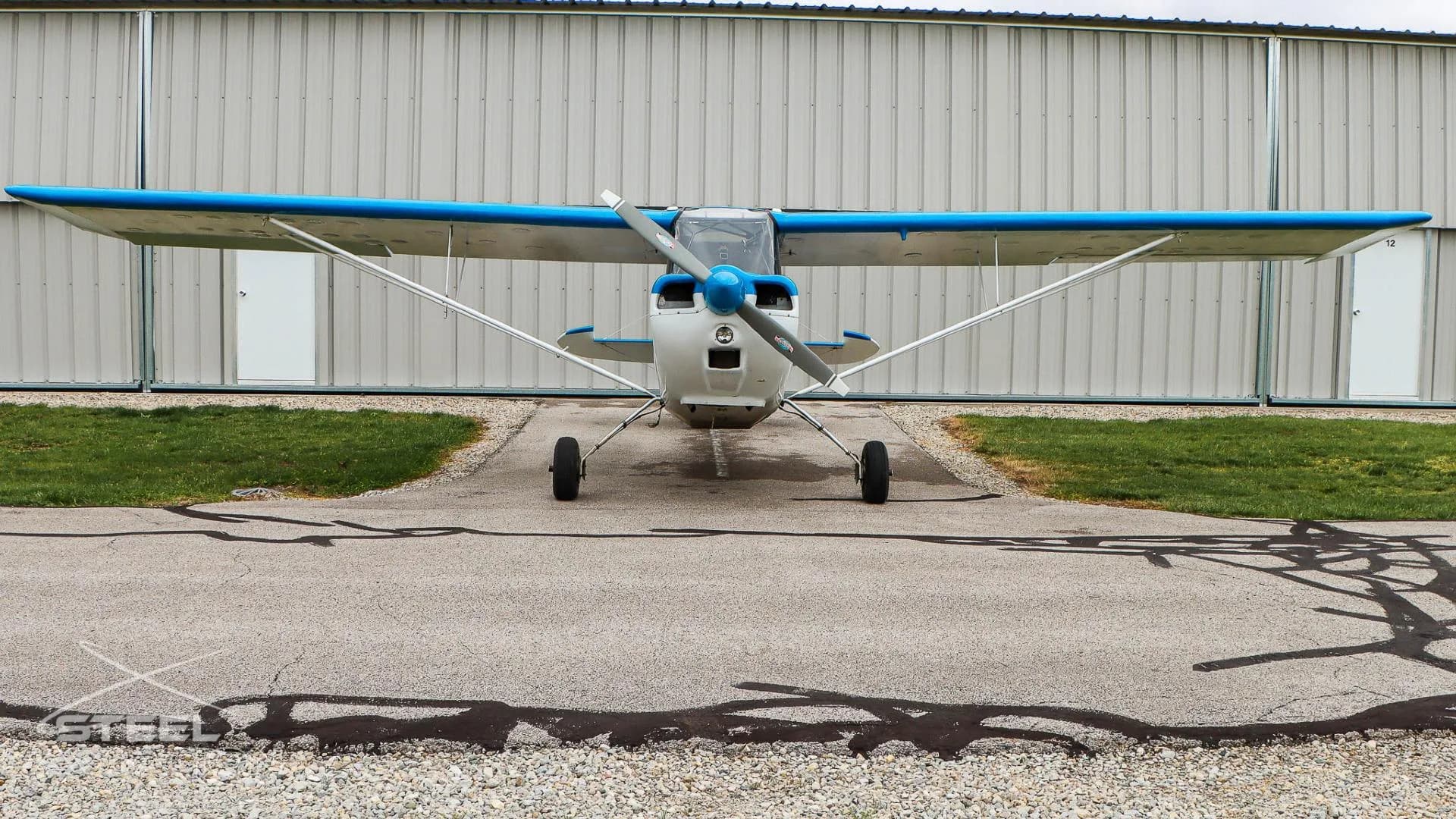 Front view of a white and blue Bellanca 7GCBC Citabria aircraft parked on an asphalt ramp.