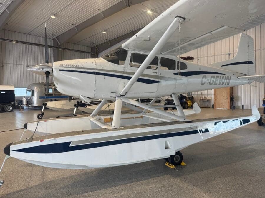 A Skywagon 185 floatplane is parked inside a hangar.