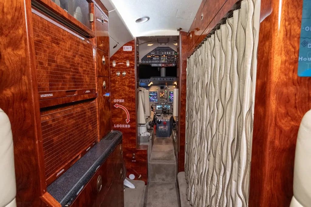 Interior view of the aircraft cabin showing the aisle leading to the cockpit.