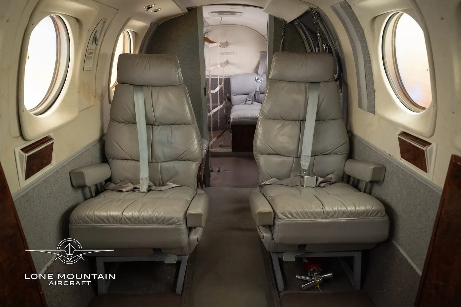 A close-up view of two grey leather passenger seats in the aircraft's cabin, looking towards the rear.