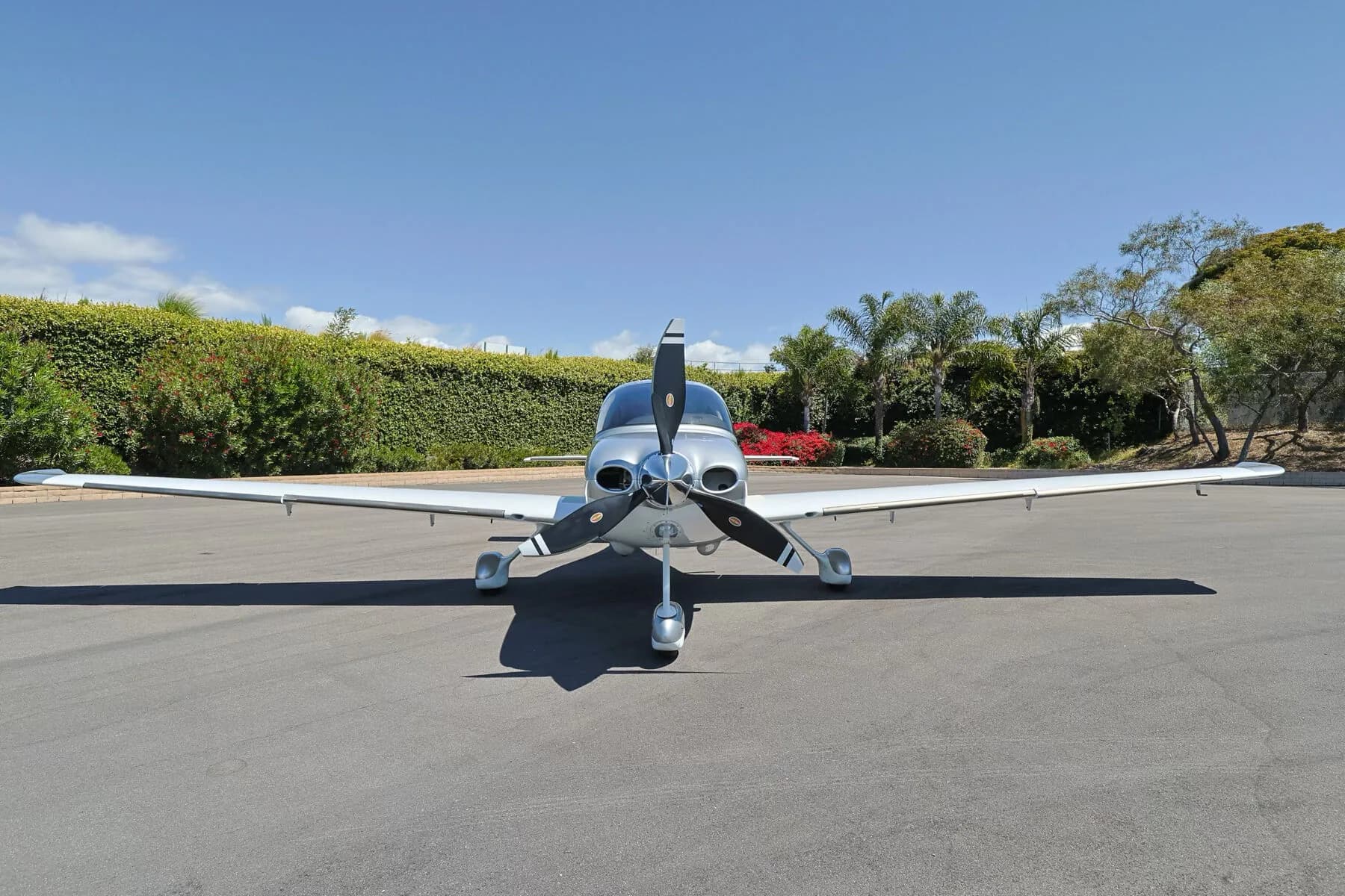 Front view of a silver and white Cirrus SR22T (N54LW) with its propeller centered, parked on an tarmac.