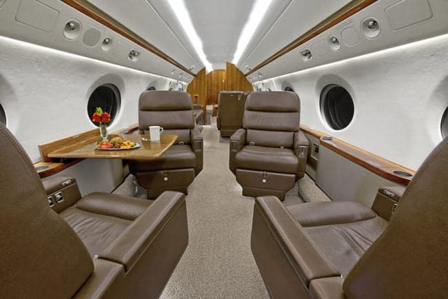View of the aircraft interior with leather seats and a table set for a meal.