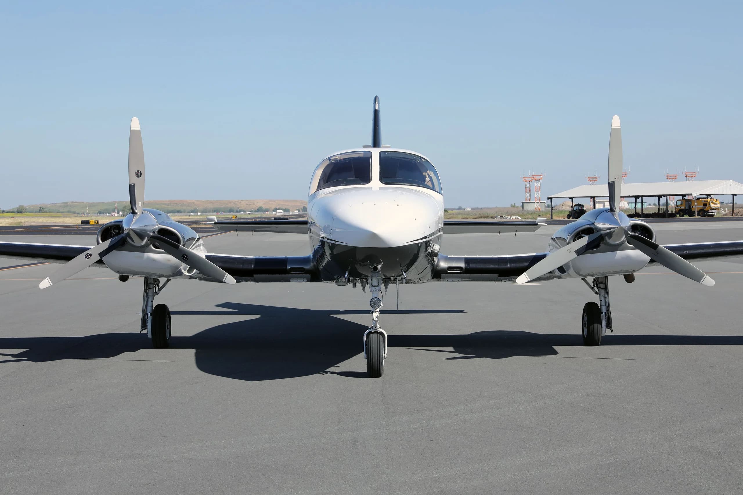 A head-on view of the white and grey twin-engine Cessna 414 Chancellor aircraft, N477MG, parked on an asphalt tarmac.