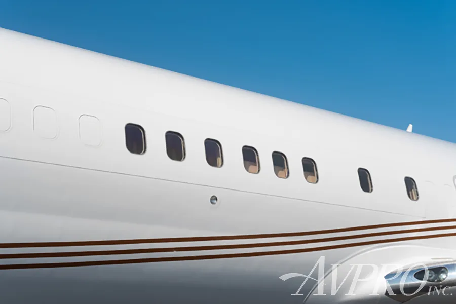 A close-up view of the white fuselage and rectangular windows of a Boeing 737 business jet with brown stripes.