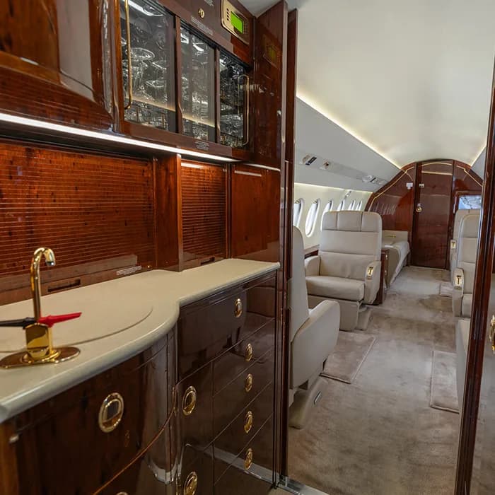 The aircraft galley features wood cabinetry and a sink.
