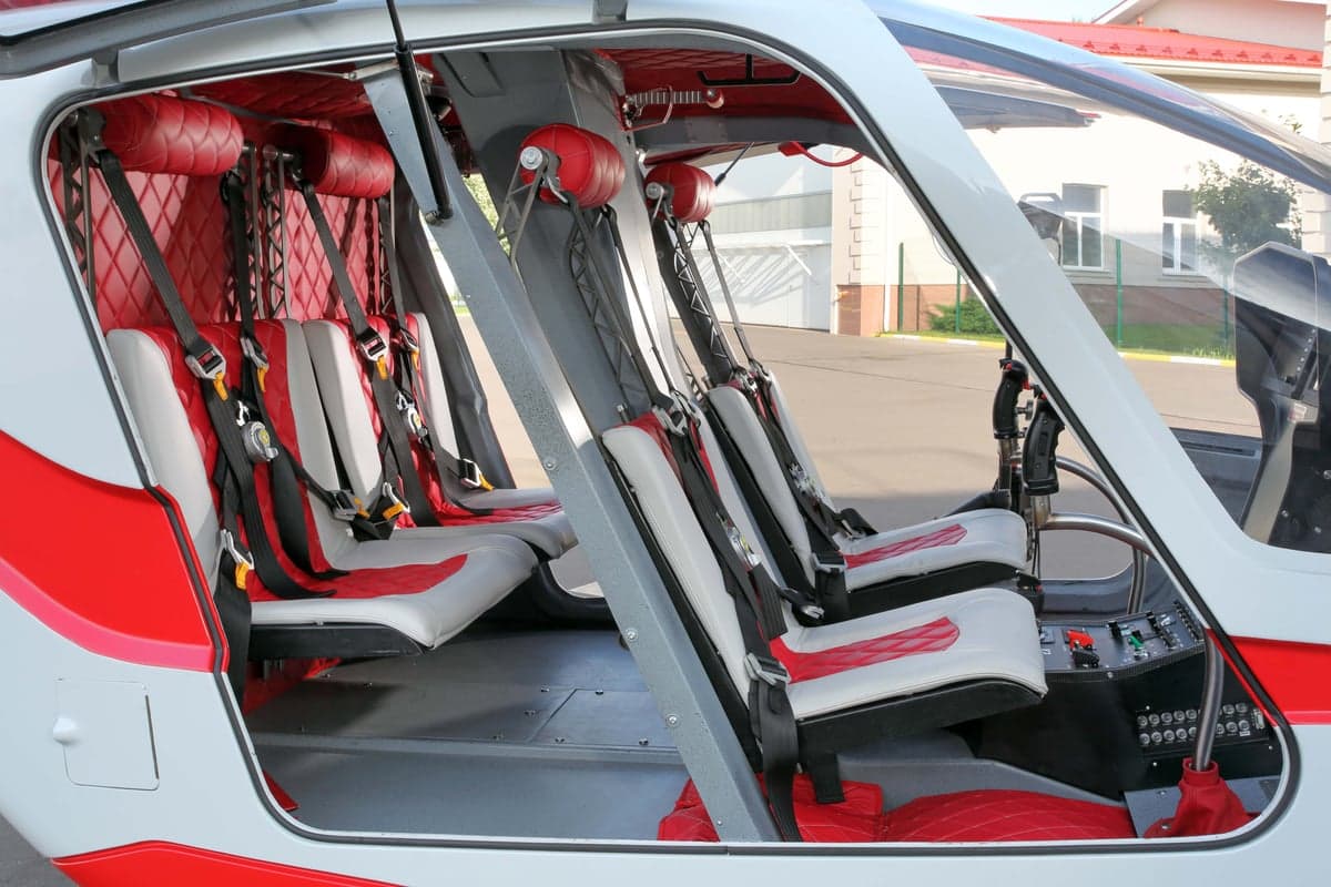 The interior of the helicopter features red and white seats with seatbelts.