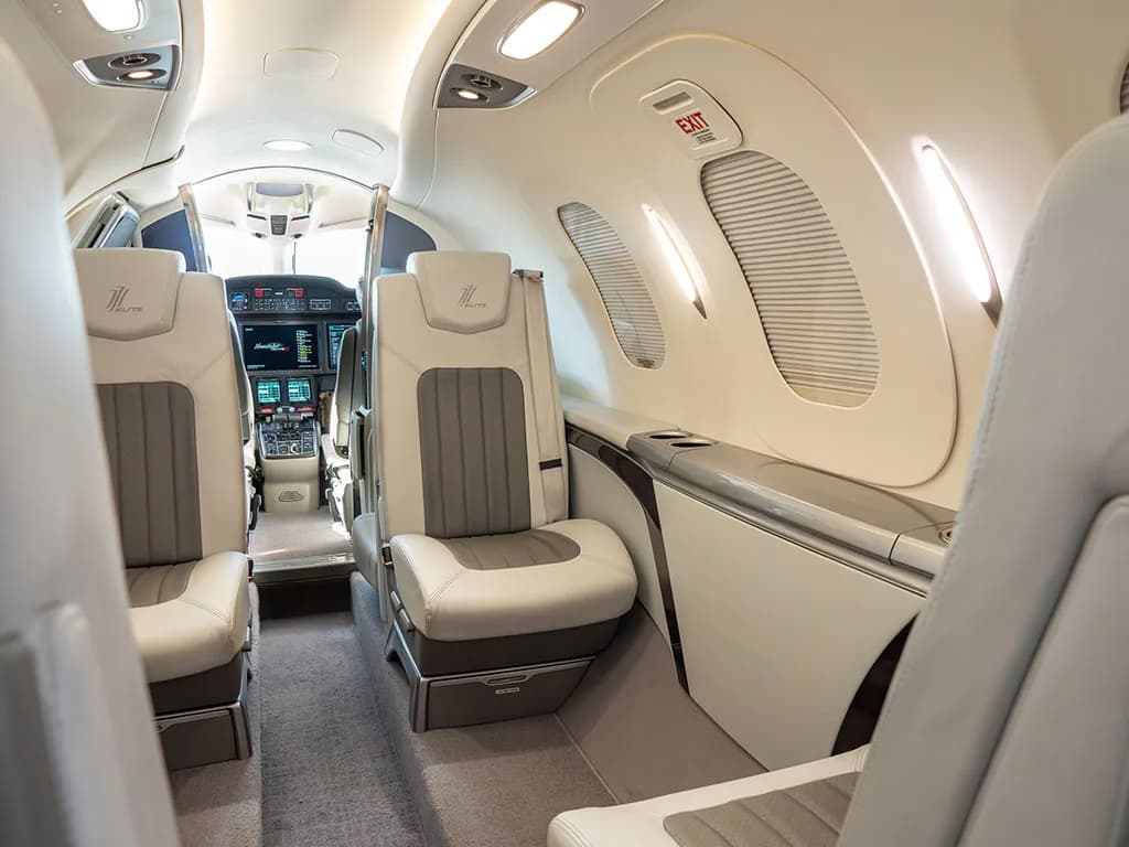 An angled view of the HondaJet's interior cabin, showing light grey and white leather seats and a glimpse of the cockpit.