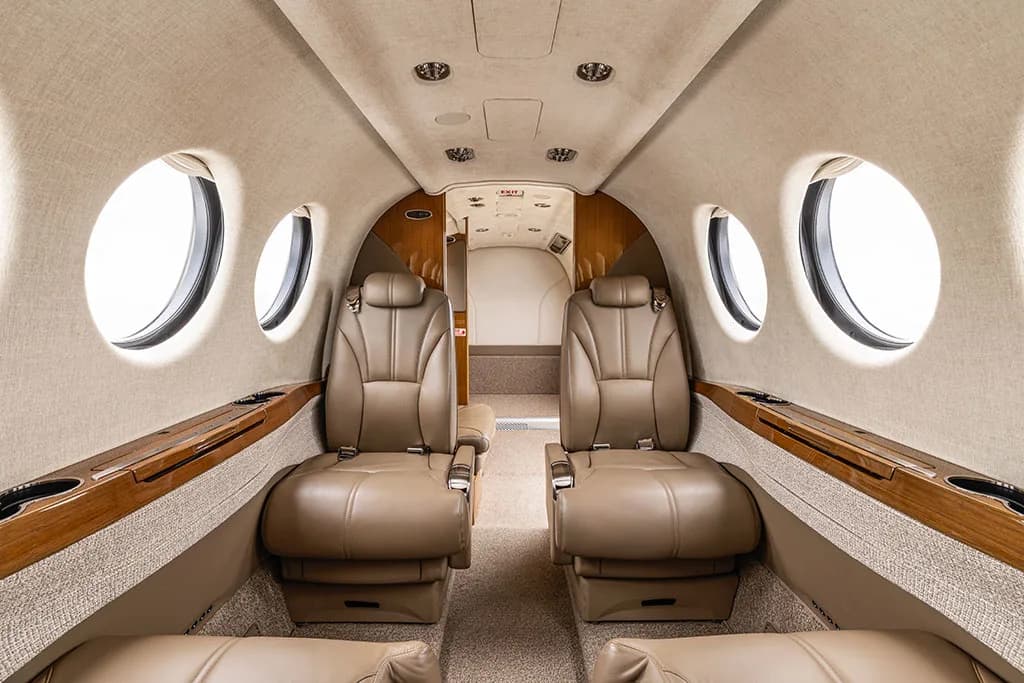 The aircraft's beige leather cabin interior, looking towards the rear with two rows of seats visible.