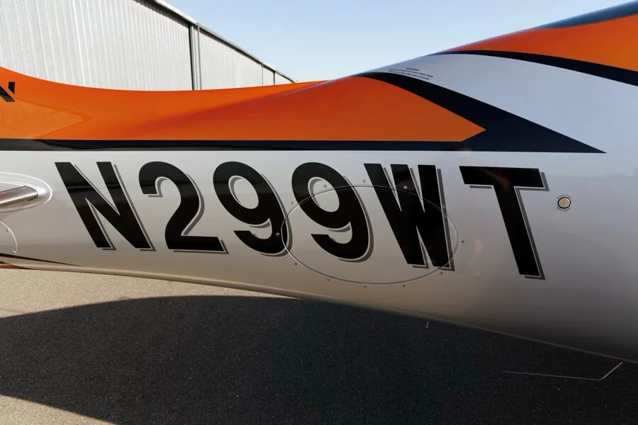 Close-up of the registration N299WT on the side of an orange and silver Cirrus SR22T GTS aircraft.