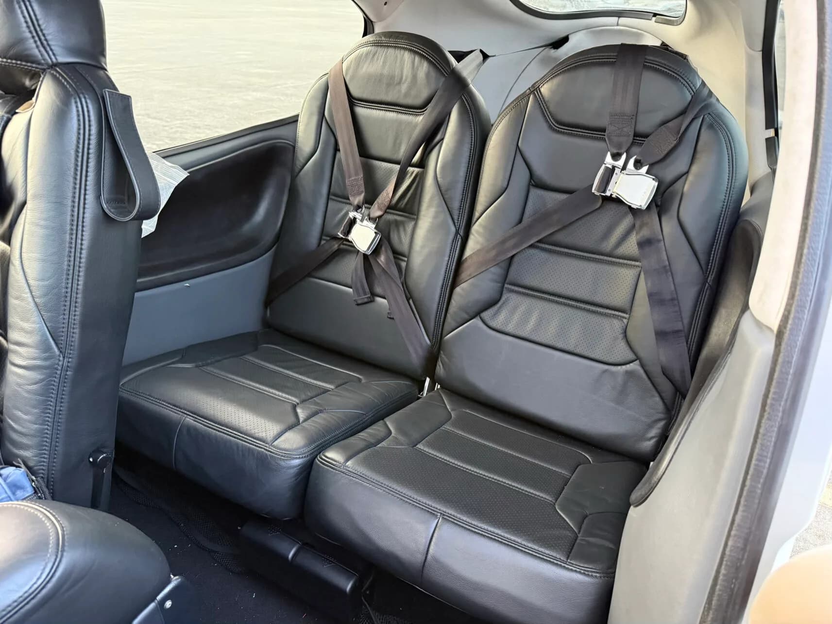 The two black leather rear seats of a Cirrus SR22 aircraft cabin.