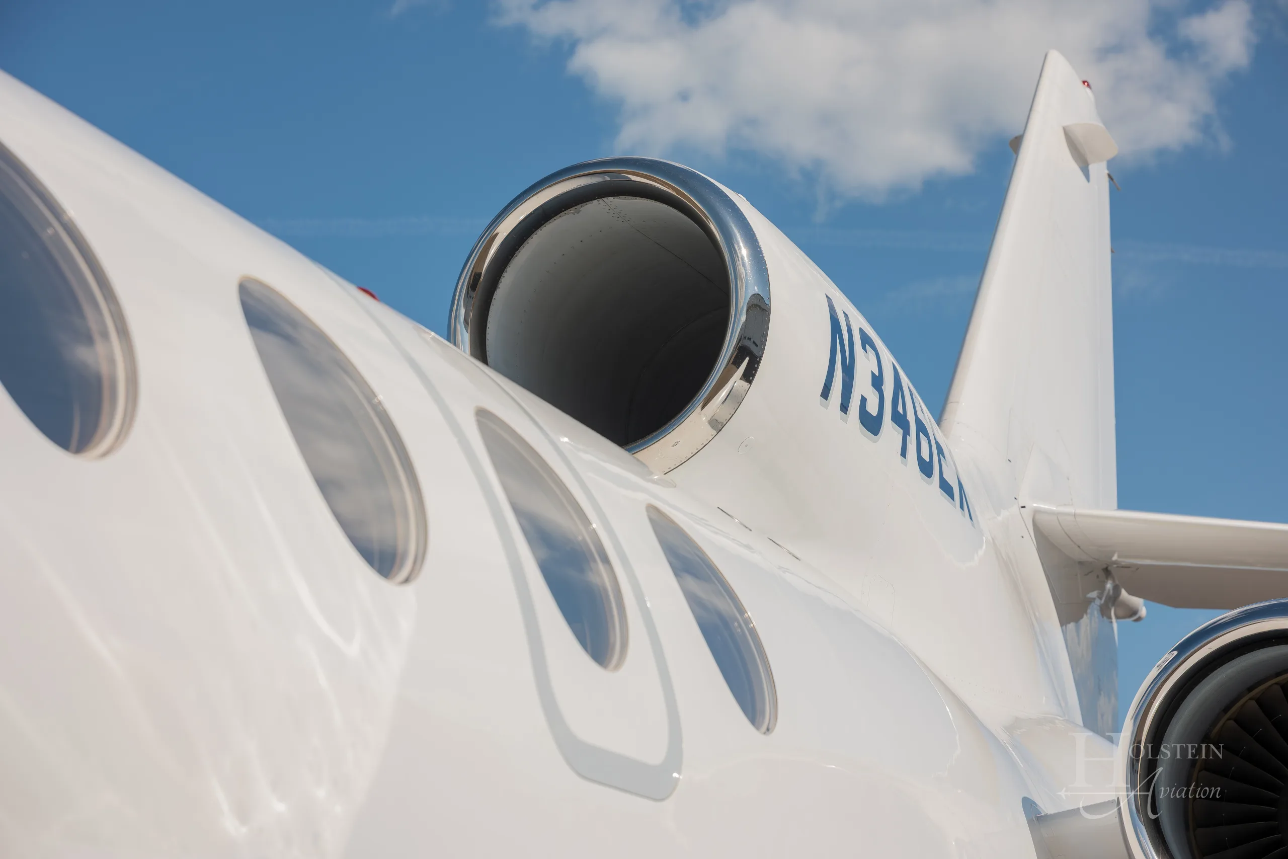 A close-up view of the tail and rear fuselage of the white Dassault Falcon 900EX, N346EX, showing the registration and windows.