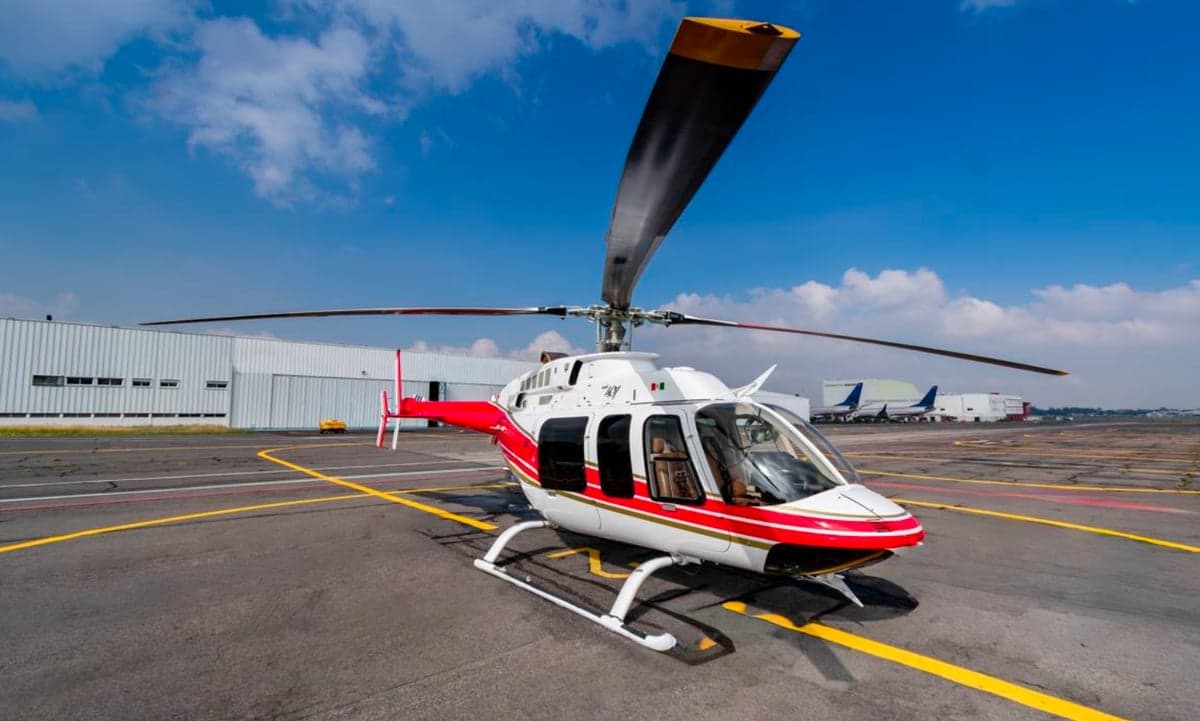 Front view of a white and red Bell 407 helicopter on the tarmac.
