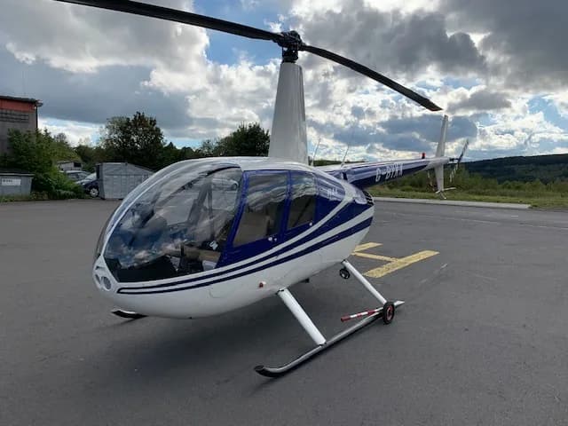 Robinson R44 Raven with blue and white paint scheme on a helipad.