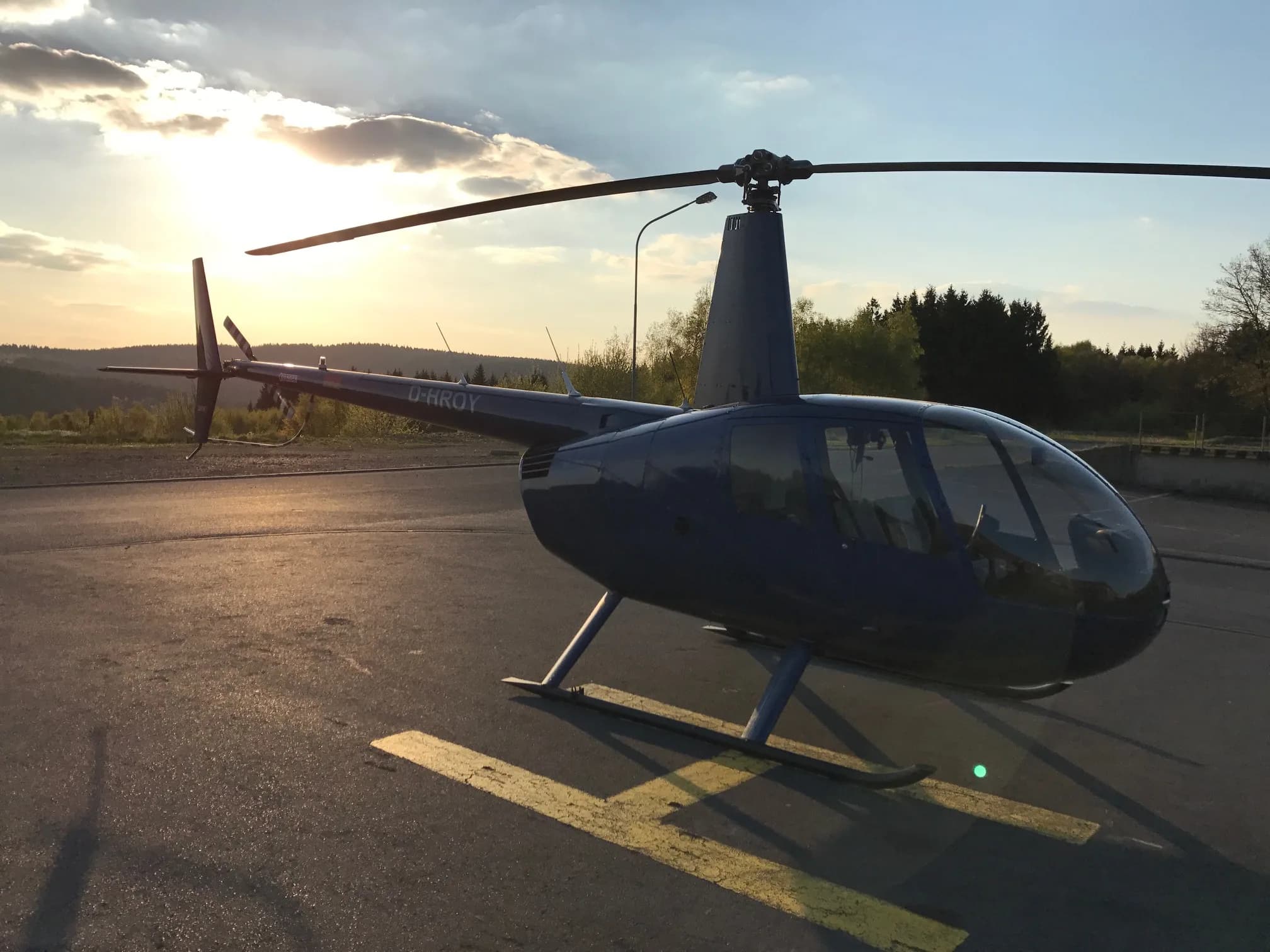 Robinson R44 Raven I OE-XXQ helicopter on the ground at sunset.