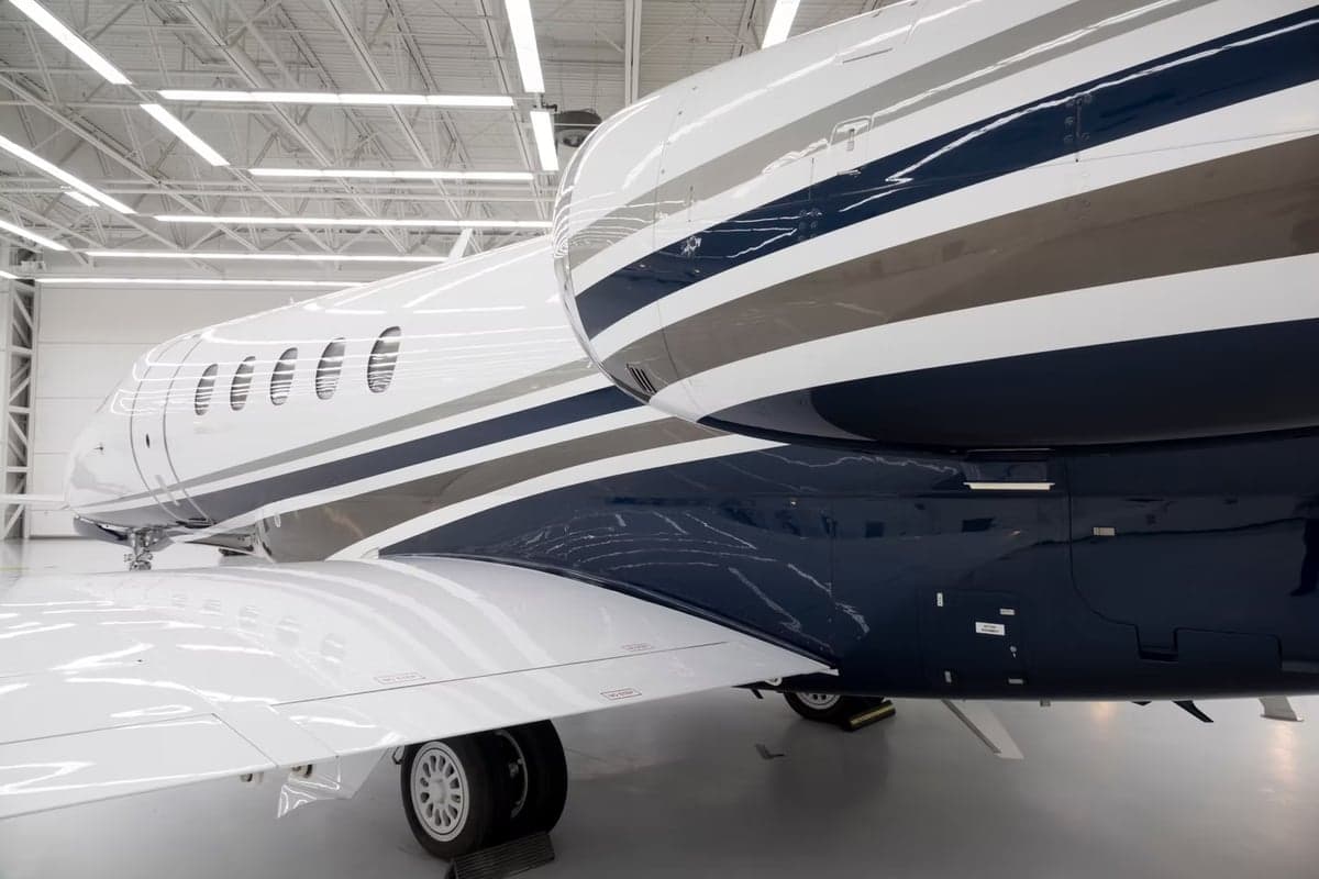 Close-up of the N83PM aircraft's fuselage and wing in a hangar.