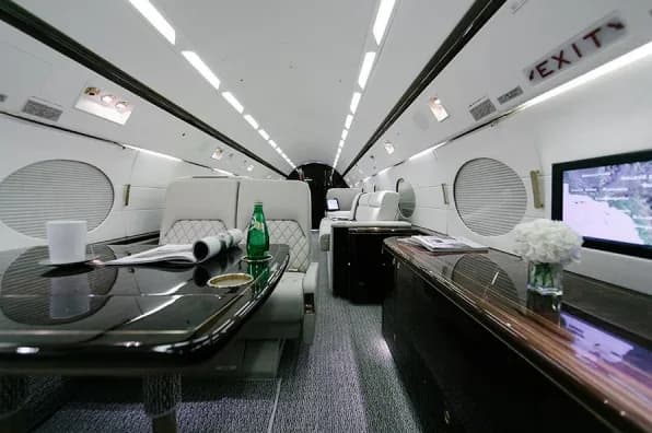 Interior view of an aircraft cabin with leather seats and wood trim.