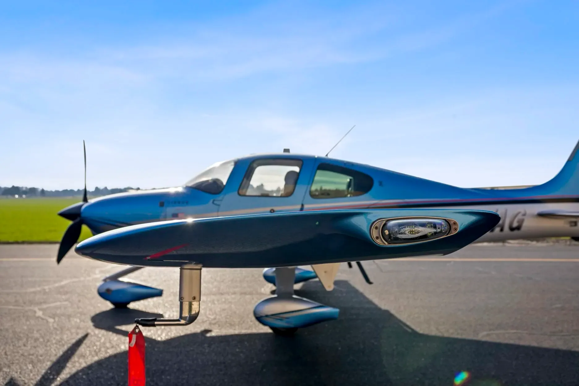 A close-up side view of the blue and silver Cirrus SR22T aircraft on an airfield.