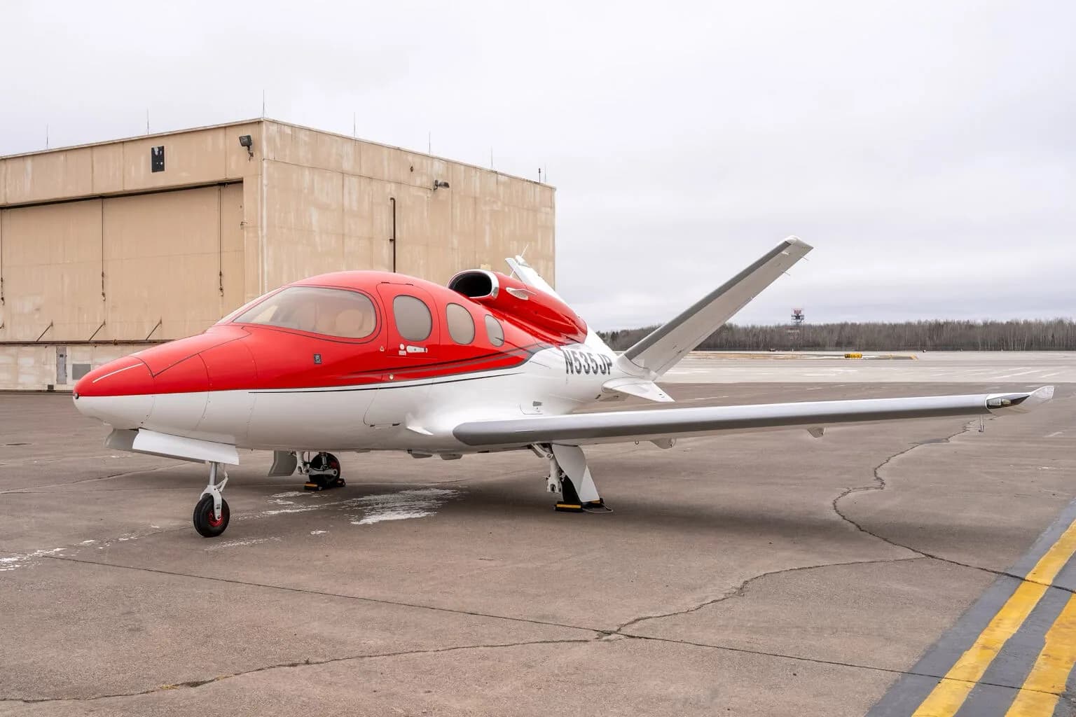 Side view of a red and white Cirrus Vision Jet (N535JP) parked on the tarmac.