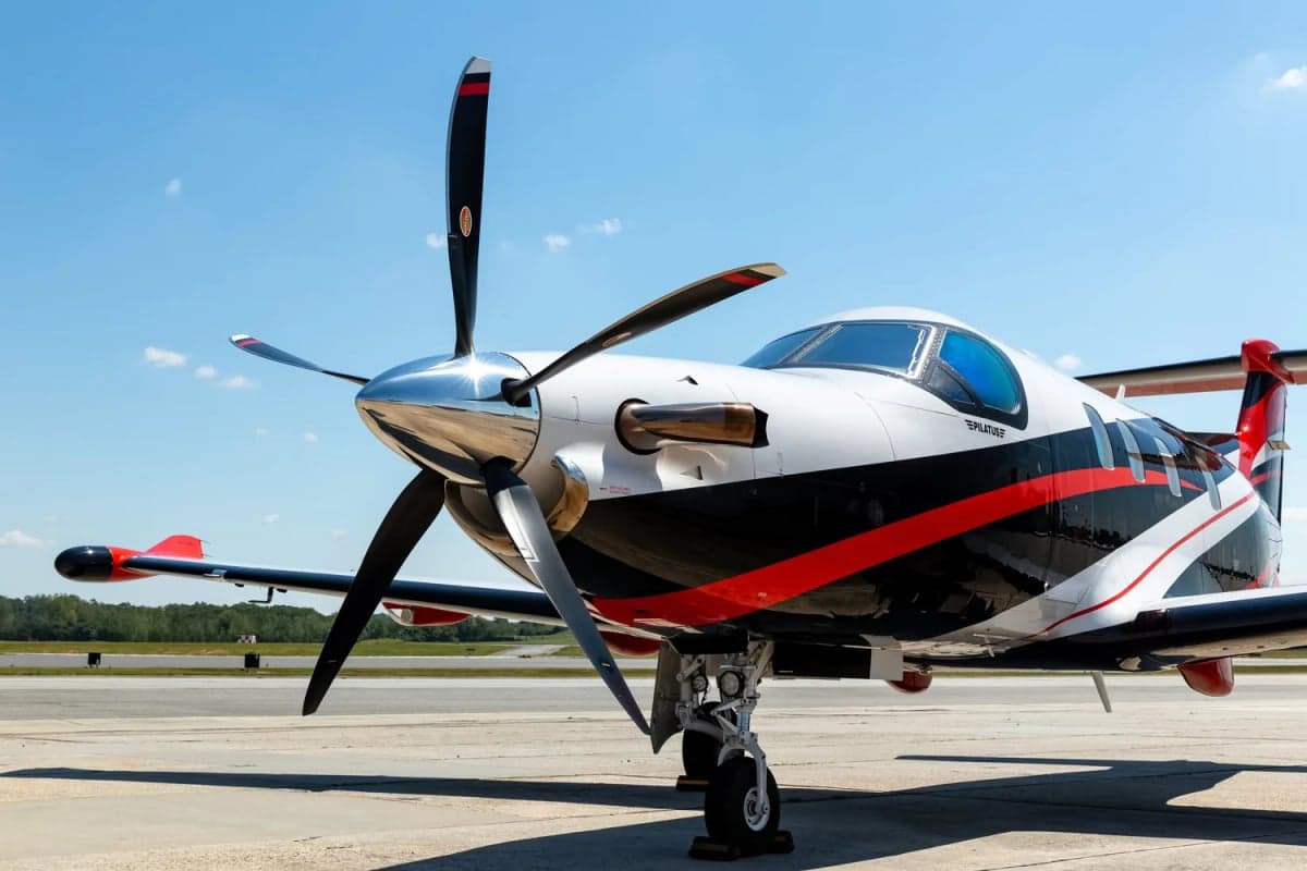 Pilatus PC-12 on the tarmac with a black, white, and red paint scheme.