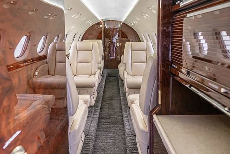 View of the aircraft's interior with leather seats and wood paneling.