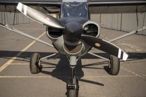 Front view of a gray and red Cubcrafters XCub showing the propeller and landing gear.