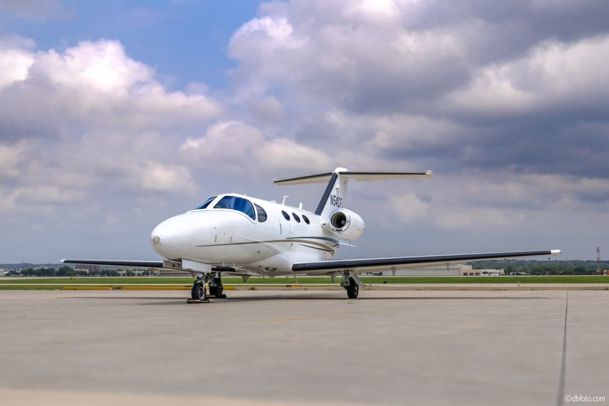 Front view of a white Cessna Citation with black and gold accents on the tarmac.