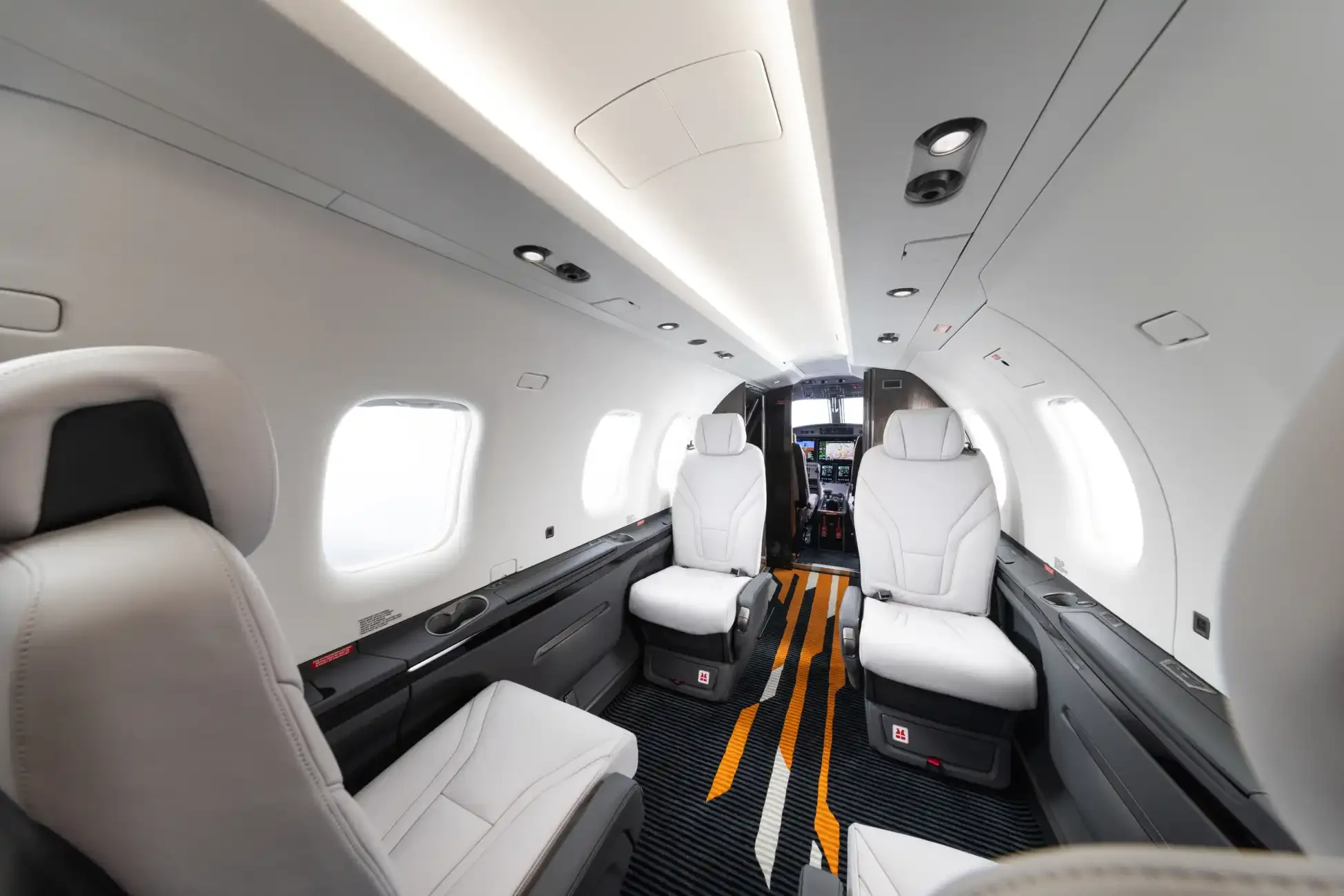 View of the aircraft's interior showing the white leather seats and orange and gray striped carpet.